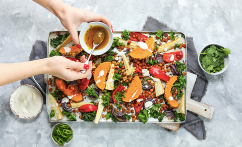 Drizzling over tray of butternut and vegetables